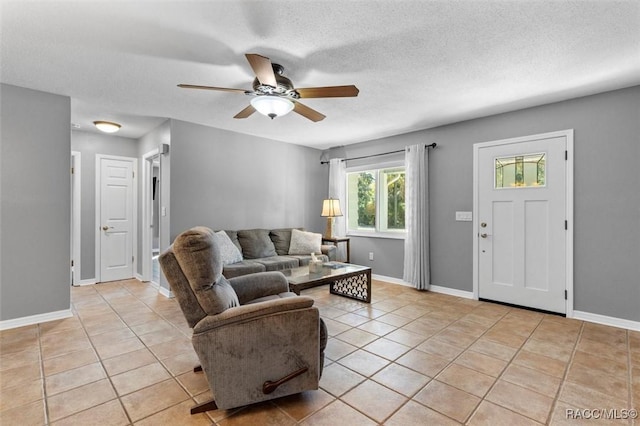 living room featuring light tile patterned floors, baseboards, a textured ceiling, and a ceiling fan