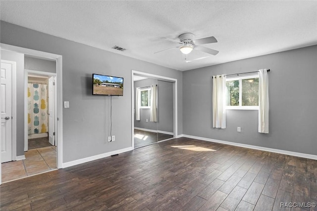 unfurnished bedroom with visible vents, a textured ceiling, a closet, and wood finished floors