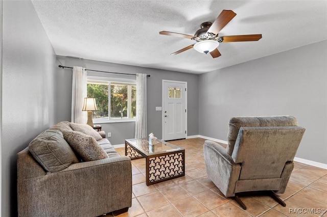 living room with light tile patterned flooring, ceiling fan, a textured ceiling, and baseboards