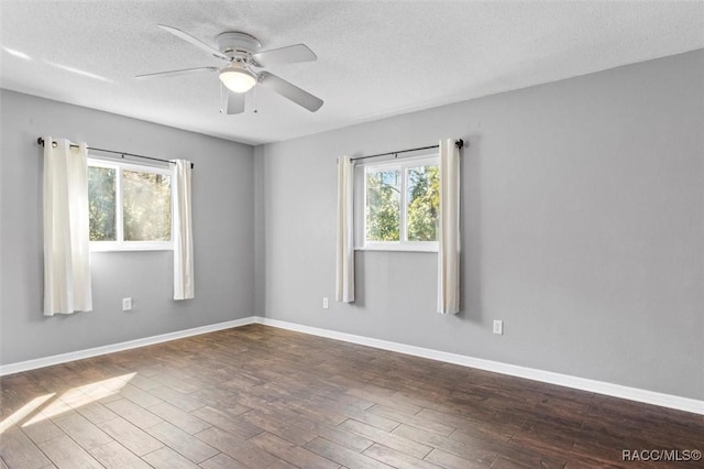 spare room featuring a wealth of natural light, a textured ceiling, baseboards, and wood finished floors