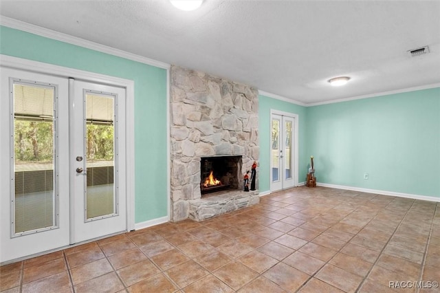 unfurnished living room with visible vents, ornamental molding, a stone fireplace, french doors, and a wealth of natural light