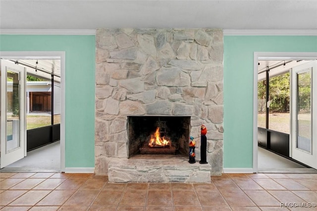 unfurnished living room featuring baseboards, a stone fireplace, crown molding, and tile patterned flooring