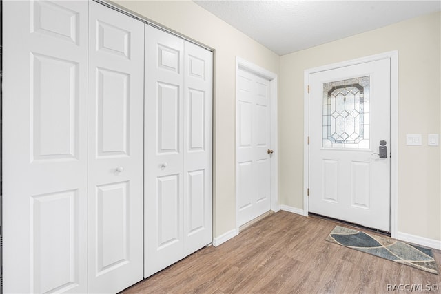 foyer entrance with a textured ceiling and light wood-type flooring