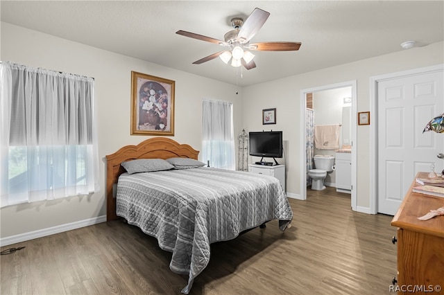 bedroom featuring dark hardwood / wood-style flooring, ensuite bath, and ceiling fan