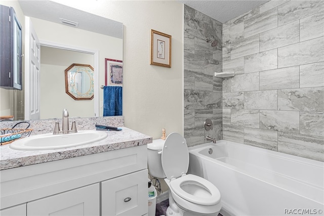 full bathroom featuring vanity, tiled shower / bath combo, a textured ceiling, and toilet