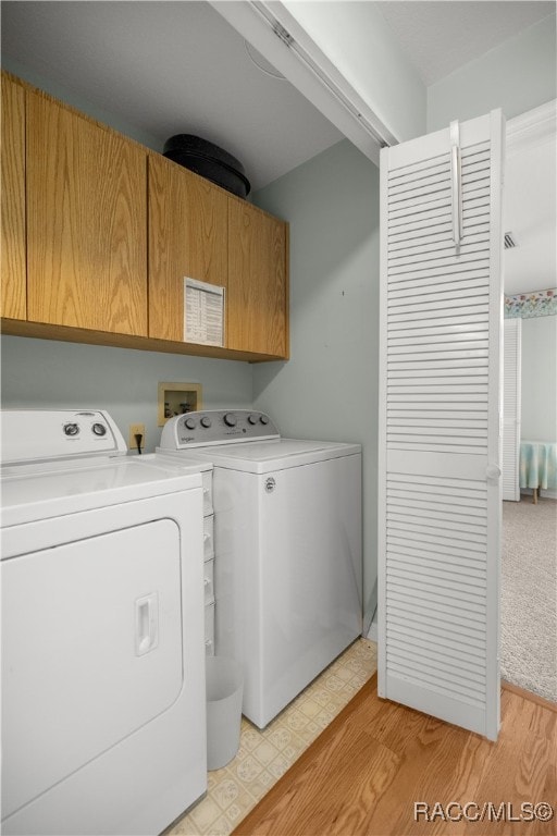 laundry area featuring cabinets, light hardwood / wood-style floors, and washing machine and clothes dryer