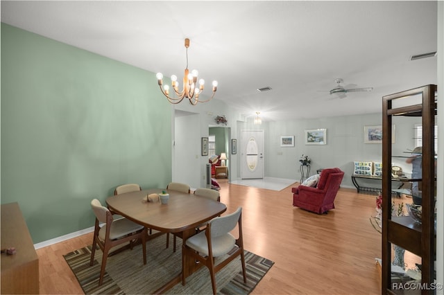 dining room with ceiling fan with notable chandelier and light wood-type flooring