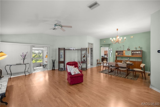 living room with ceiling fan with notable chandelier, lofted ceiling, and light hardwood / wood-style flooring