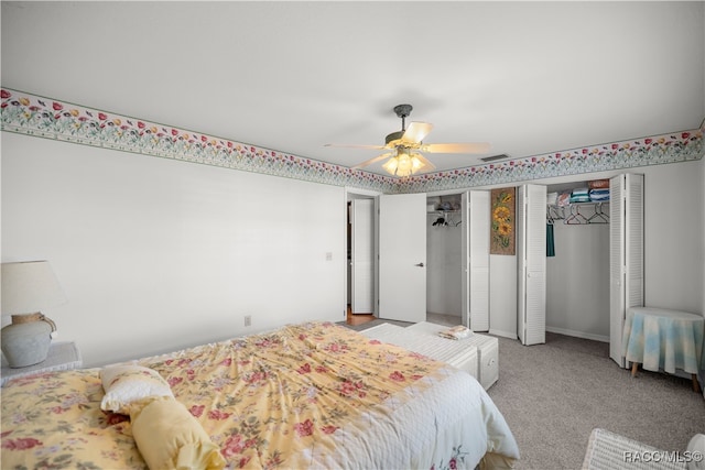 carpeted bedroom with ceiling fan and two closets