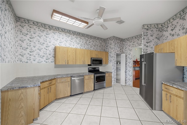 kitchen featuring ceiling fan, light tile patterned flooring, light stone counters, and appliances with stainless steel finishes