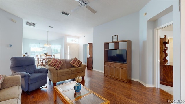 living room with dark hardwood / wood-style flooring and ceiling fan with notable chandelier