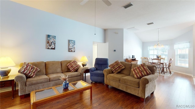 living room with ceiling fan with notable chandelier, dark wood-type flooring, and vaulted ceiling