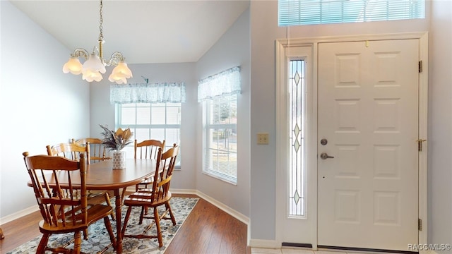 dining room with hardwood / wood-style flooring, vaulted ceiling, and a chandelier