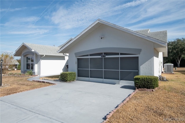 view of front of home featuring a garage, a front lawn, and central air condition unit