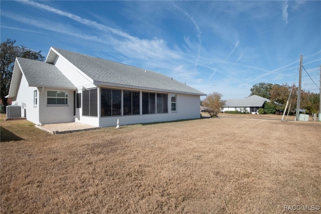 back of house featuring a sunroom, central AC unit, and a lawn