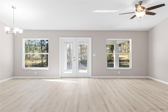 empty room with french doors, light wood-type flooring, and ceiling fan with notable chandelier