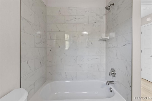 bathroom with toilet and tiled shower / bath