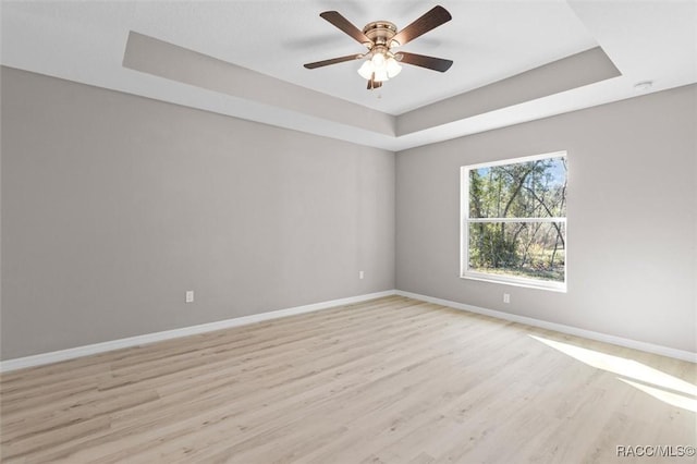 spare room featuring light wood-type flooring, ceiling fan, and a tray ceiling