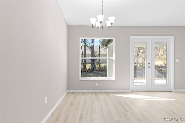 unfurnished dining area featuring light hardwood / wood-style floors, french doors, and a chandelier