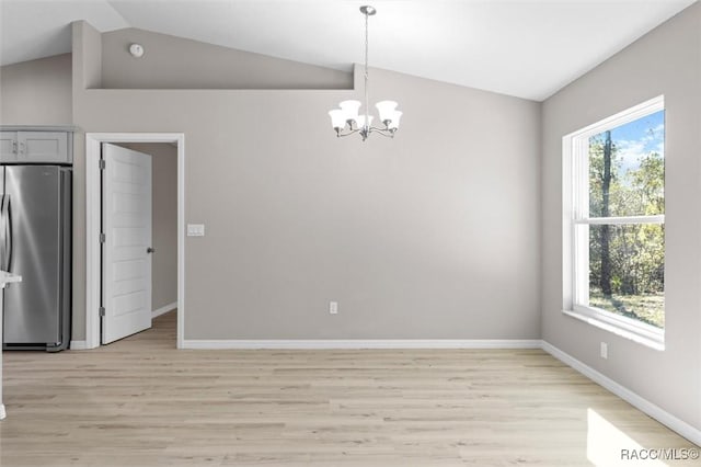 unfurnished dining area with an inviting chandelier, vaulted ceiling, and light hardwood / wood-style flooring