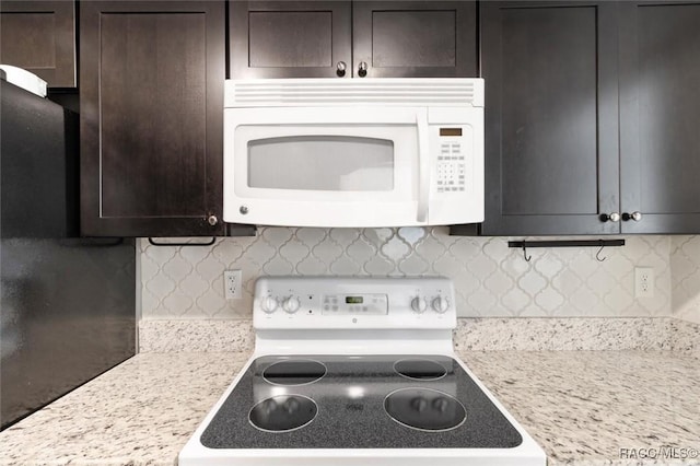 kitchen with dark brown cabinets, stove, light stone countertops, and backsplash