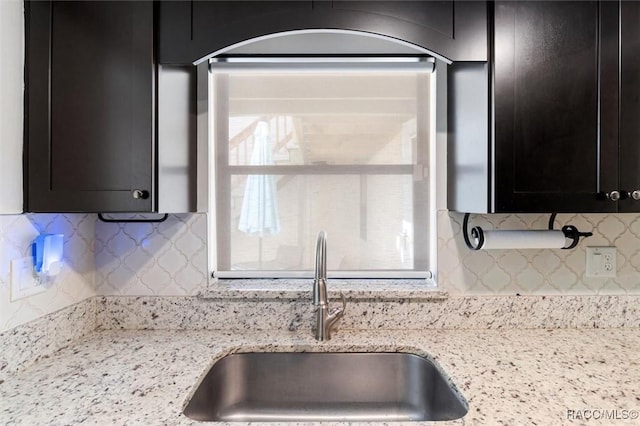 kitchen featuring light stone countertops, backsplash, and sink