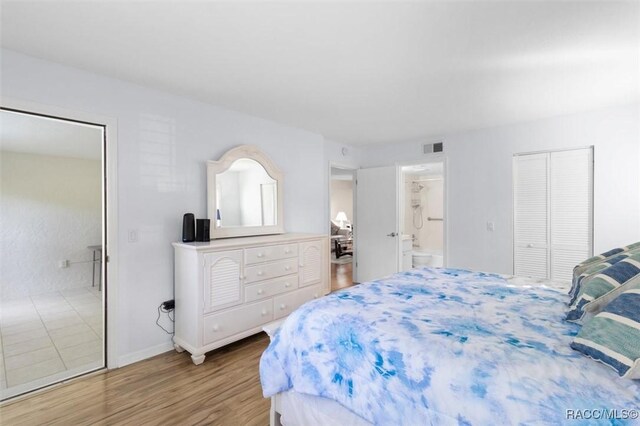 bedroom with hardwood / wood-style floors and ensuite bathroom