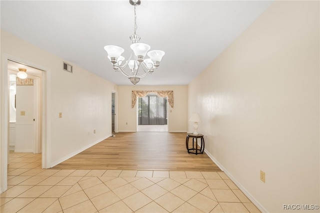 empty room with light tile patterned floors and a chandelier