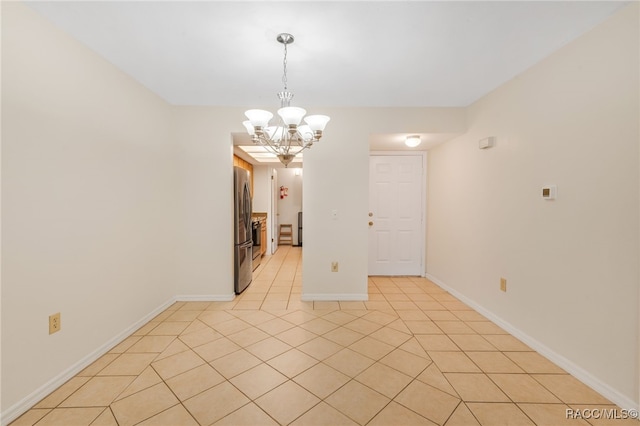 spare room with a chandelier and light tile patterned floors