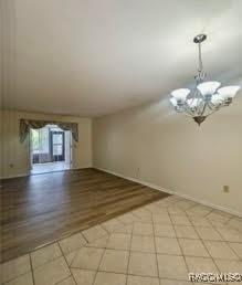 unfurnished room featuring light hardwood / wood-style flooring and a notable chandelier