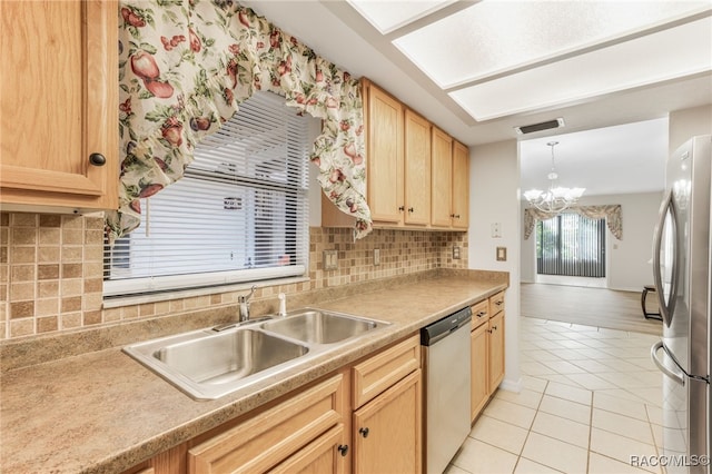 kitchen with hanging light fixtures, sink, light tile patterned floors, appliances with stainless steel finishes, and a notable chandelier