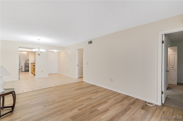 unfurnished room with a chandelier and light hardwood / wood-style flooring