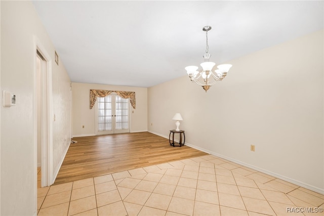 spare room with light wood-type flooring, baseboards, a chandelier, and french doors