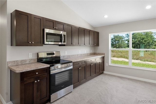 kitchen featuring dark brown cabinetry, stainless steel appliances, and lofted ceiling