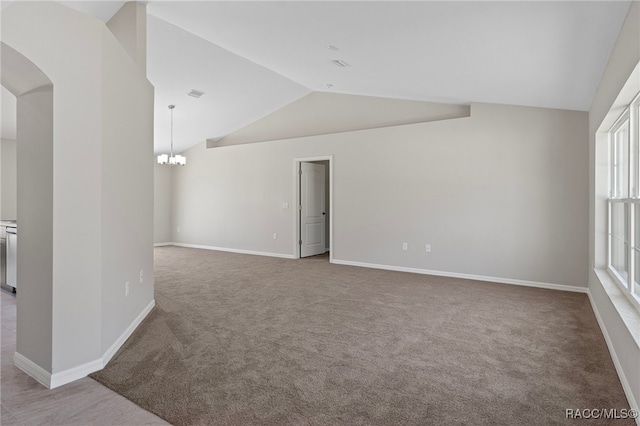 empty room featuring carpet flooring, vaulted ceiling, and an inviting chandelier