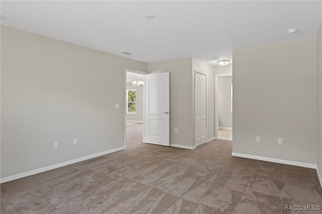 carpeted spare room with a notable chandelier