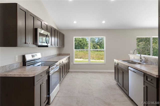 kitchen featuring sink, vaulted ceiling, light tile patterned floors, appliances with stainless steel finishes, and dark brown cabinetry