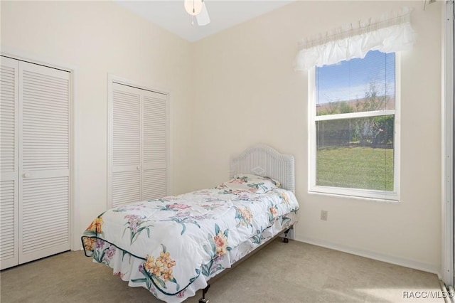 carpeted bedroom with ceiling fan and two closets