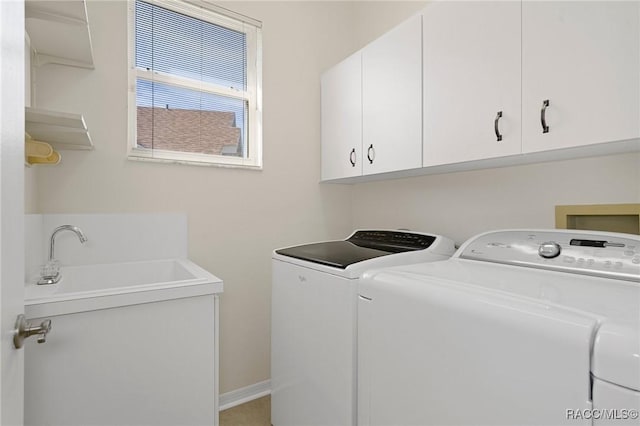 clothes washing area featuring washing machine and dryer, sink, and cabinets