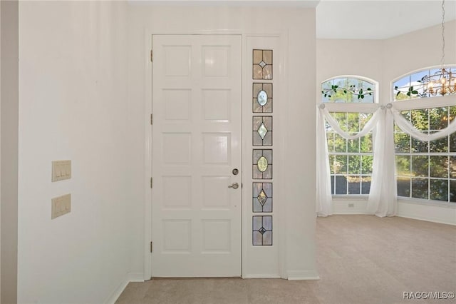 entryway with light carpet and a notable chandelier