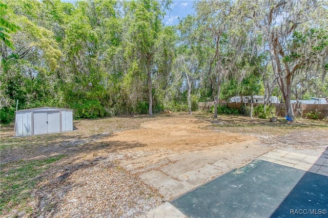 view of yard featuring fence, an outdoor structure, and a storage shed