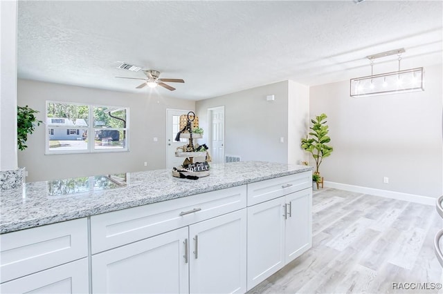 kitchen with baseboards, visible vents, a textured ceiling, and white cabinetry