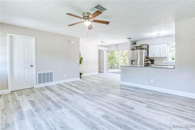 unfurnished living room with a wealth of natural light, a textured ceiling, and visible vents