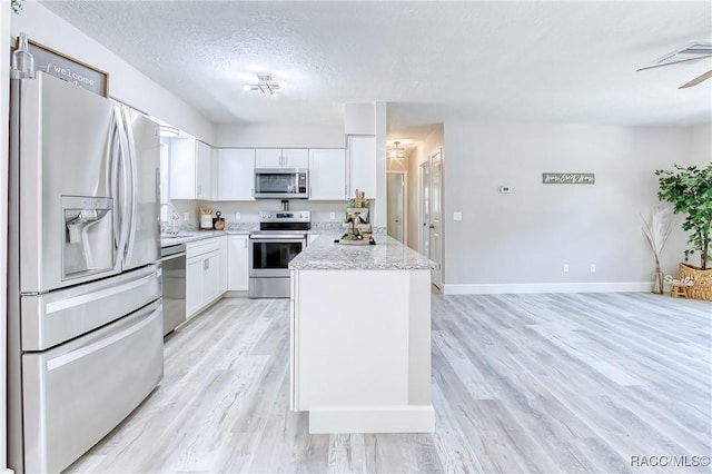 kitchen featuring white cabinets, a sink, light wood-style floors, and appliances with stainless steel finishes