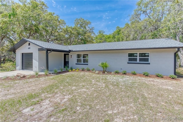 ranch-style home featuring an attached garage, a shingled roof, stucco siding, and driveway