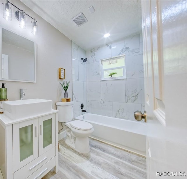 full bath with wood finished floors, visible vents, toilet, vanity, and tub / shower combination