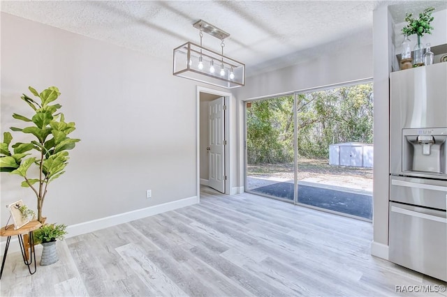 unfurnished dining area featuring a chandelier, baseboards, wood finished floors, and a textured ceiling