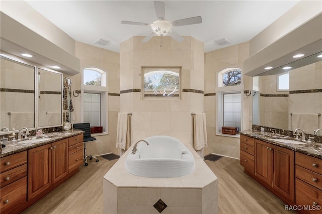 full bathroom with tile walls, wood finished floors, visible vents, and a sink