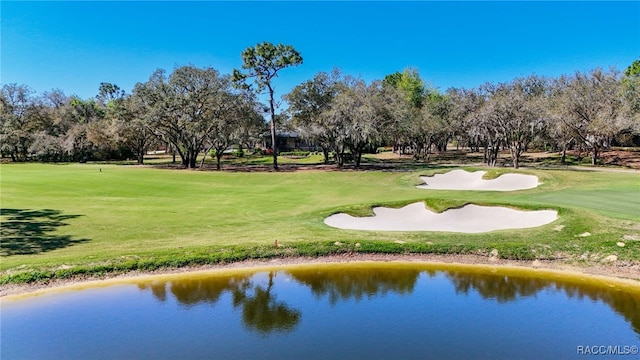 view of property's community featuring golf course view, a lawn, and a water view