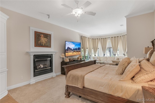 bedroom featuring a glass covered fireplace, baseboards, crown molding, and visible vents